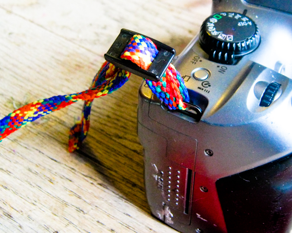 Fit the plastic slides onto the narrow webbing before you put the strap on the camera