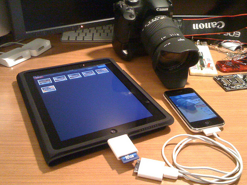 An iPad, iPhone, and Canon camera on the desk