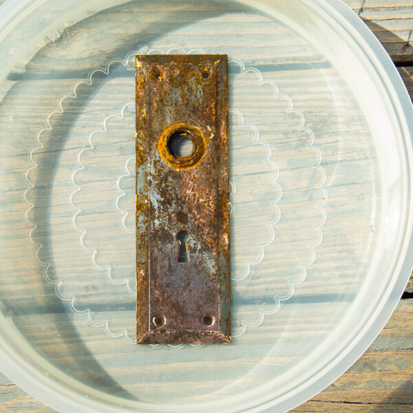 rusted antique door plate soaking in vinegar